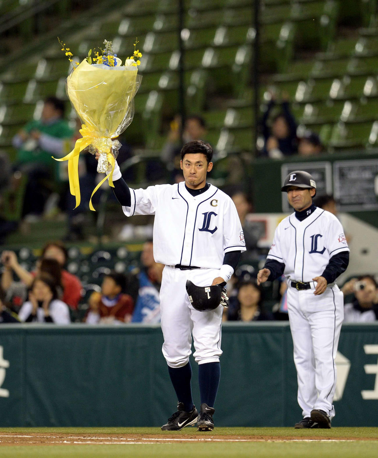 13年4月、オリックス戦の3回裏西武1死二塁、栗山巧は左前安打を放ち通算1000本安打を達成し花束を掲げる。右は奈良原浩コーチ（2013年4月16日撮影）