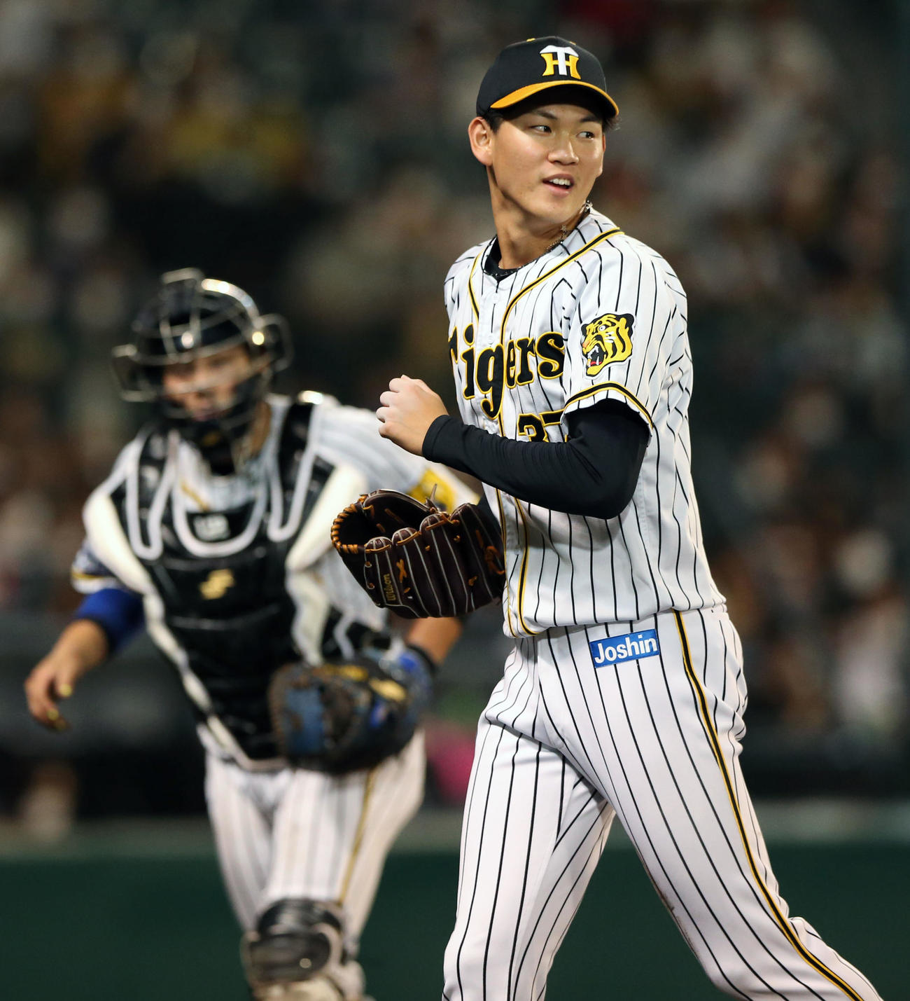 阪神対巨人　7回表巨人2死満塁、及川（手前）は代打中島から空振り三振を奪いピンチを切り抜け笑顔を見せる（撮影・上山淳一）