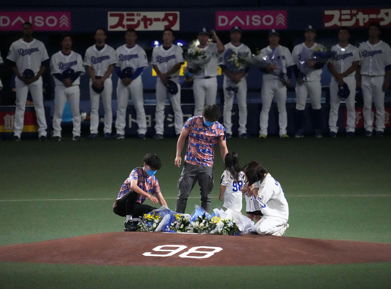 試合前、木下雄介さんの背番号「98」がデザインされたマウンドに献花する親族（撮影・森本幸一）