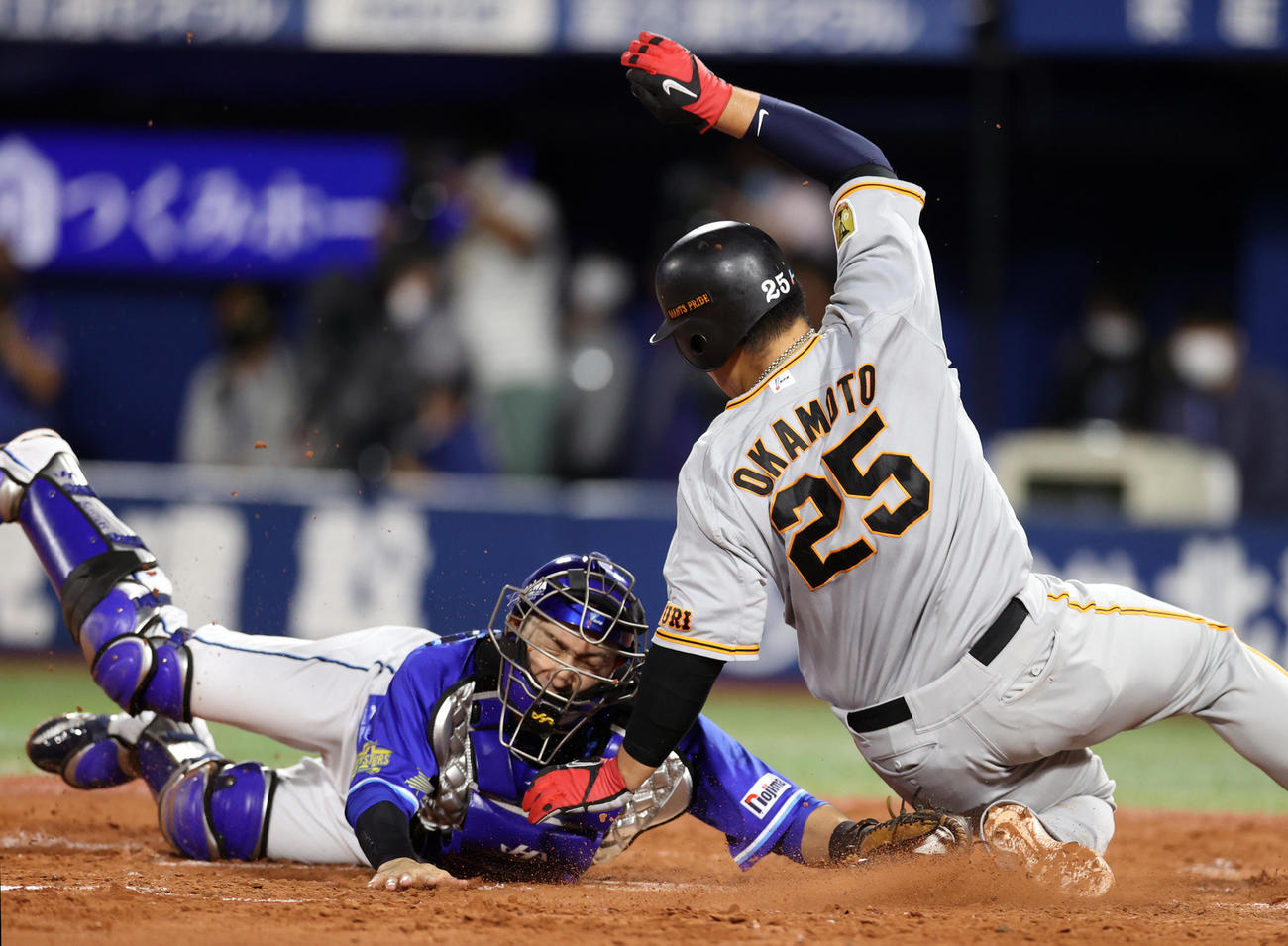 DeNA対巨人　4回表巨人2死一、二塁、中島の右前打から生還を試みるも、伊藤光（左）にタッチアウトされる岡本和（撮影・狩俣裕三）