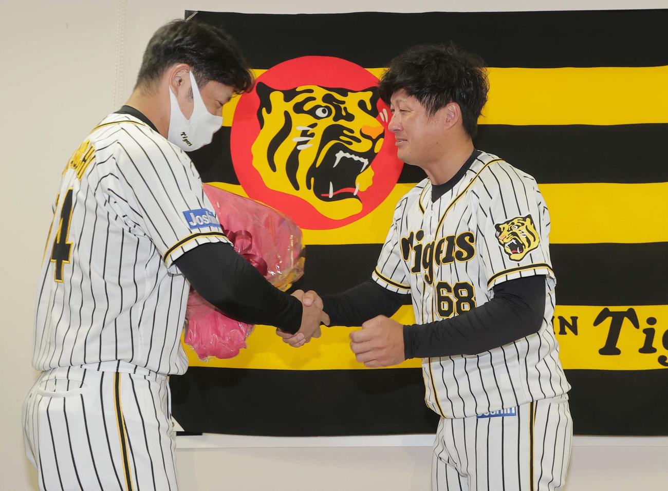 引退会見で阪神原口文仁（左）から花束を受け取り涙を流す俊介（代表撮影）
