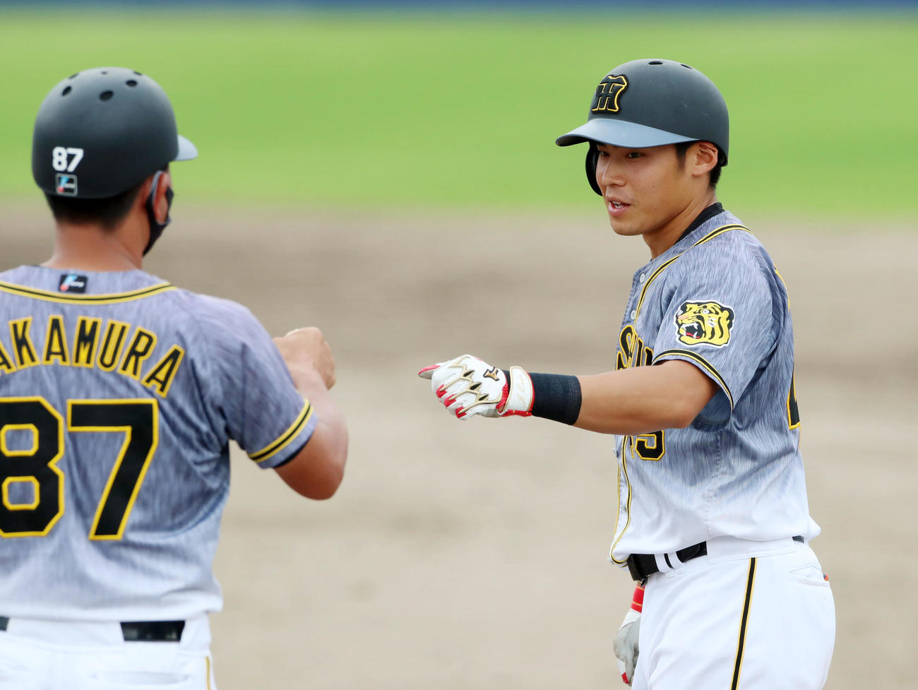 中日対阪神　9回表阪神無死、遠藤は右前打を放ち中村豊コーチ（左）と笑顔でタッチする（撮影・加藤哉）