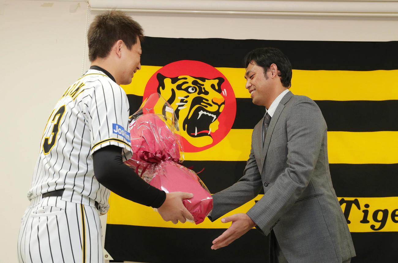 引退会見で阪神岩崎（左）から花束を受け取る桑原（撮影・前田充）