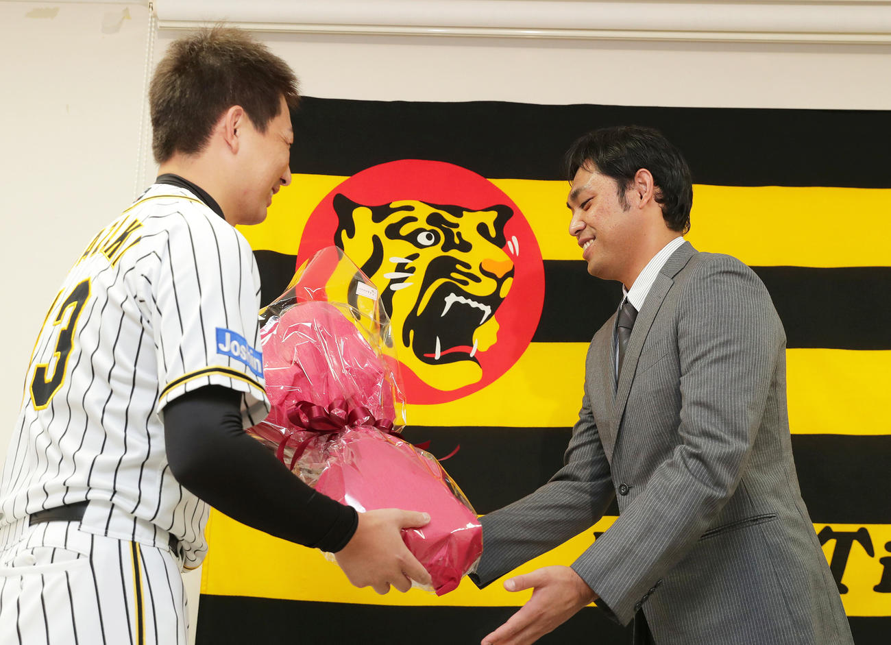 引退会見で阪神岩崎（左）から花束を受け取る桑原（撮影・前田充）