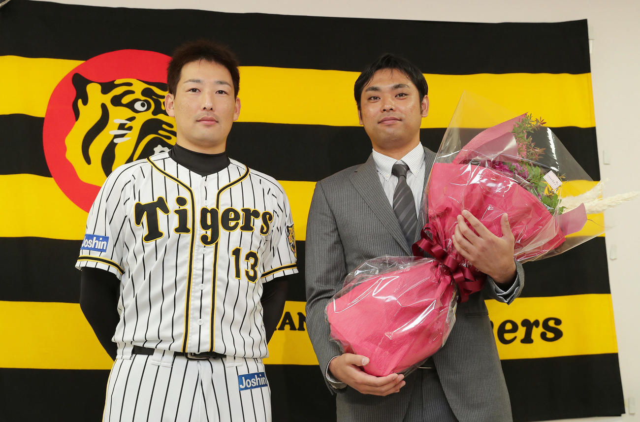 引退会見にサプライズで登場した阪神岩崎（左）から花束を受け取った桑原（撮影・前田充）