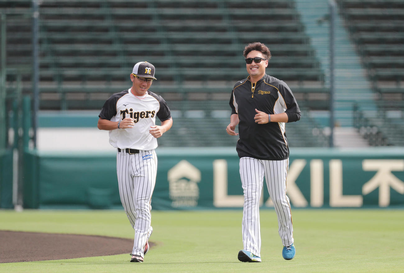 言葉を交わしながら笑顔でランニングする阪神伊藤将司（左）と秋山（撮影・前田充）