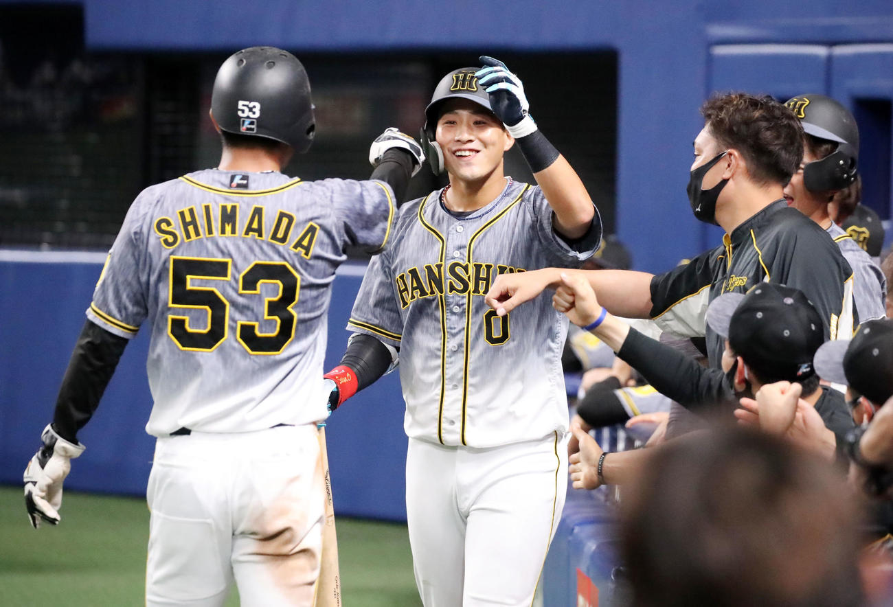 中日対阪神　9回表阪神1死三塁、木浪は左勝ち越し犠飛を放ち、生還した島田（左）と笑顔でエアタッチ（撮影・加藤哉）
