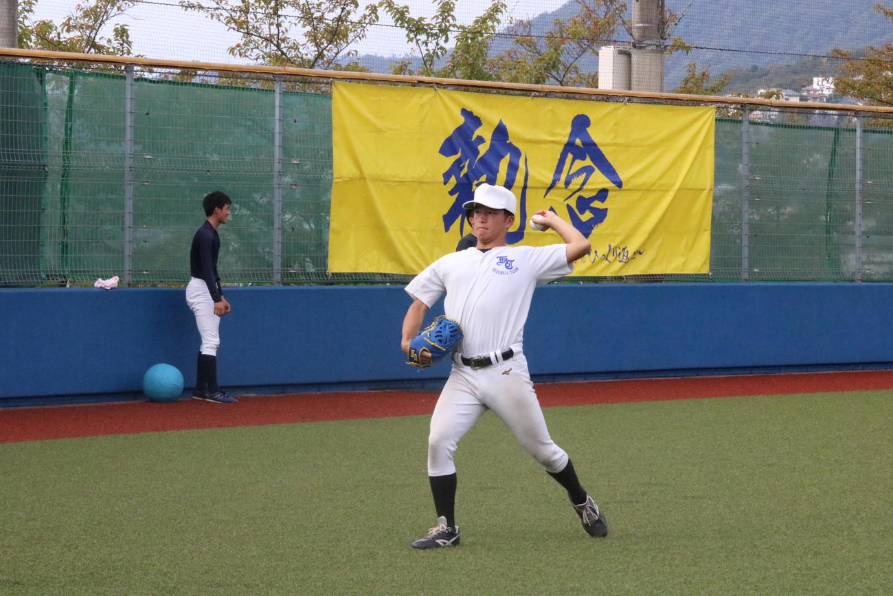 関学大の黒原拓未投手は「執念」と書かれた横断幕の前でキャッチボールを行う（撮影・林亮佑）