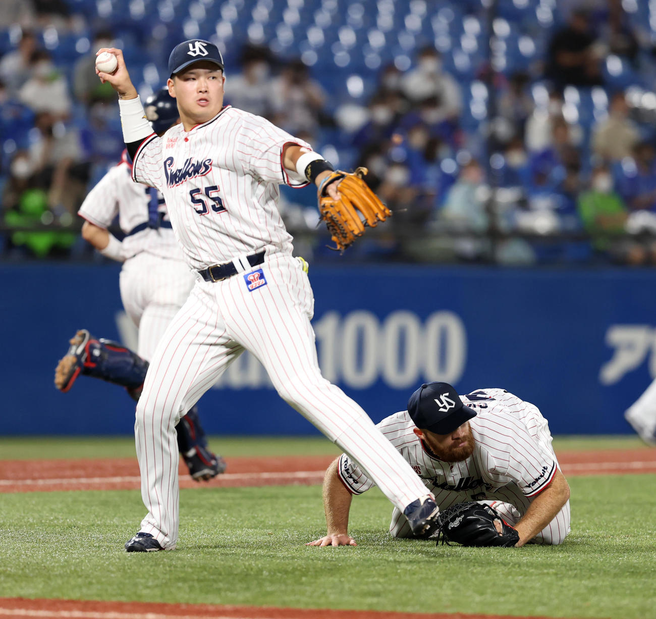 ヤクルト対DeNA 5回表DeNA無死一塁、宮国の送りバントでかがむサイスニード（右）。左は送球する村上（撮影・浅見桂子）