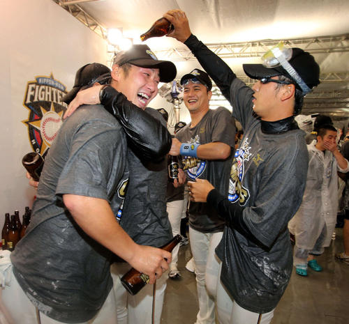 12年10月2日 優勝ビール掛け 日本ハム中田翔(左)へビールを掛ける斎藤佑樹。中央は金子誠