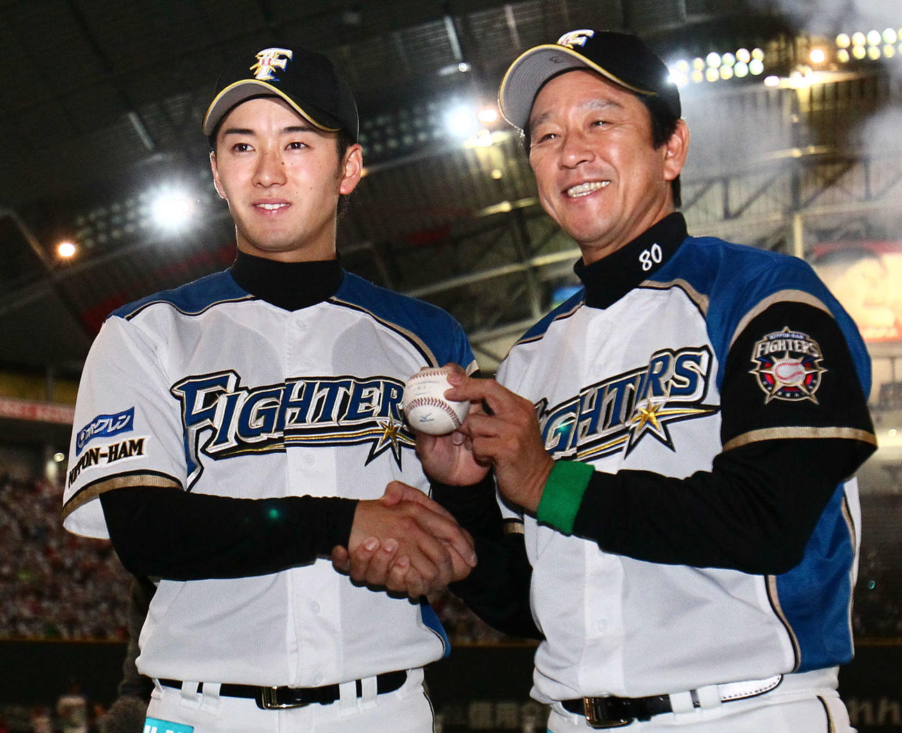 12年3月30日、西武戦で完投勝利を挙げた斎藤とポーズを決める日本ハム栗山監督（右）