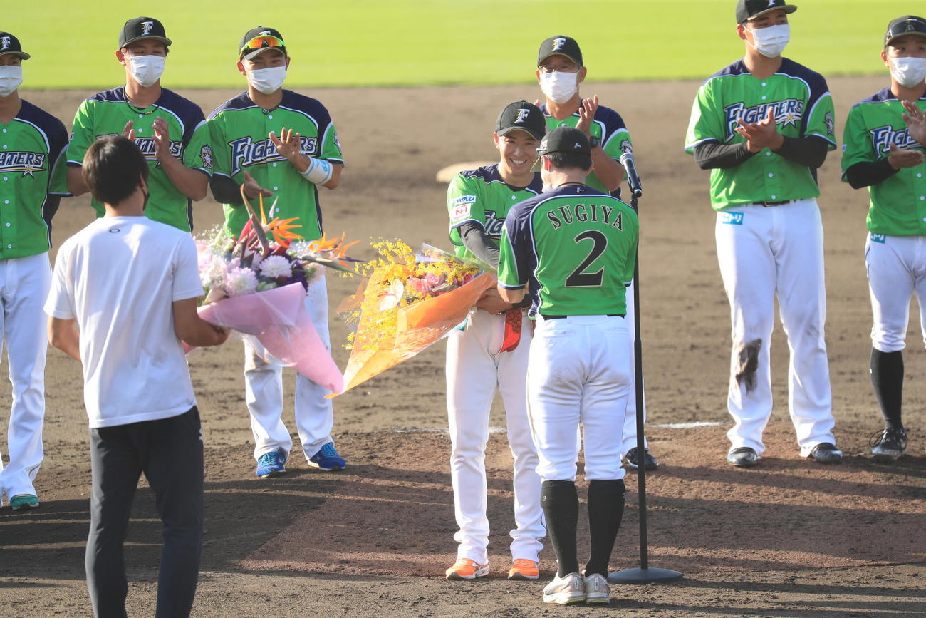 杉谷から笑顔で花束を受け取る日本ハム斎藤（代表撮影）