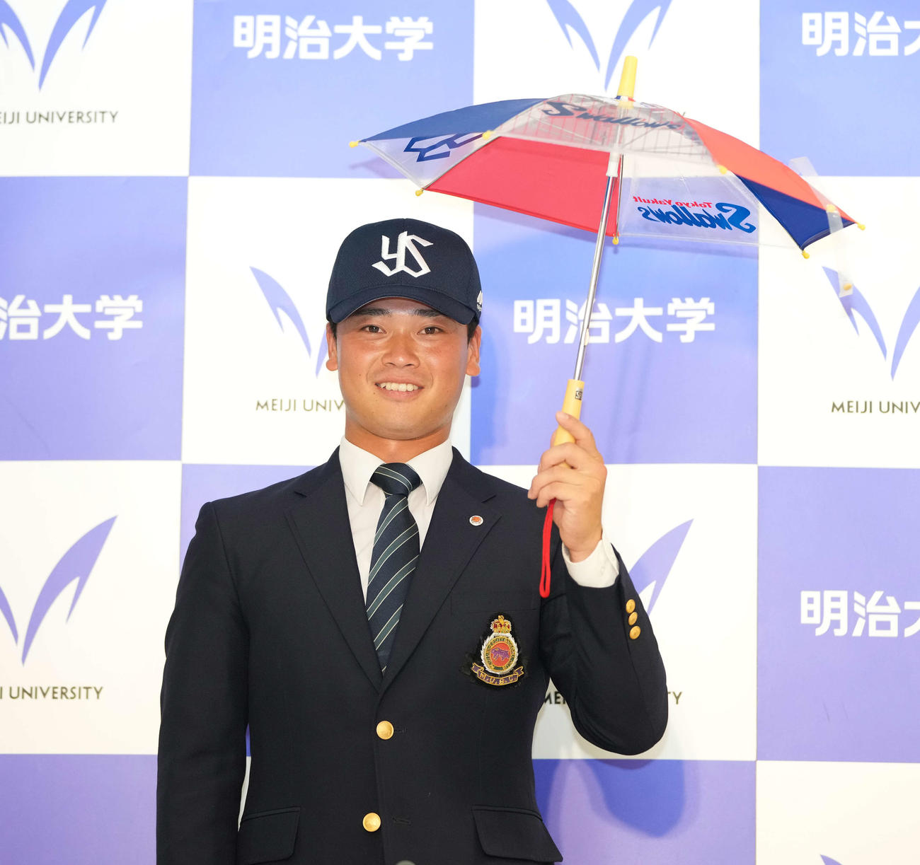 ヤクルトにドラフト2位で指名された明大・丸山は傘を振りながら笑顔（撮影・鈴木みどり）