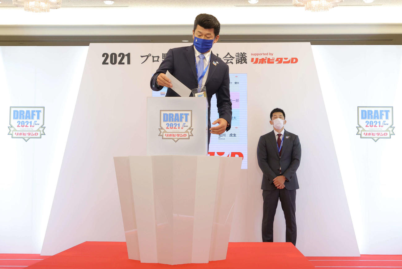 1位指名で市和歌山・小園の抽選でくじを引くDeNA三浦監督。後方は阪神矢野監督（代表撮影）