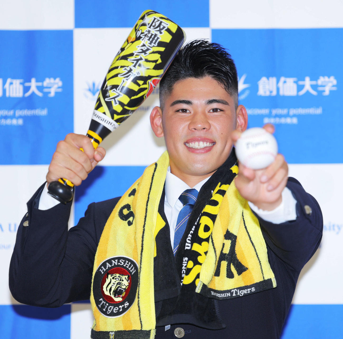 阪神2位指名を受け、グッズを手に写真に納まる創価大・鈴木（撮影・河田真司）