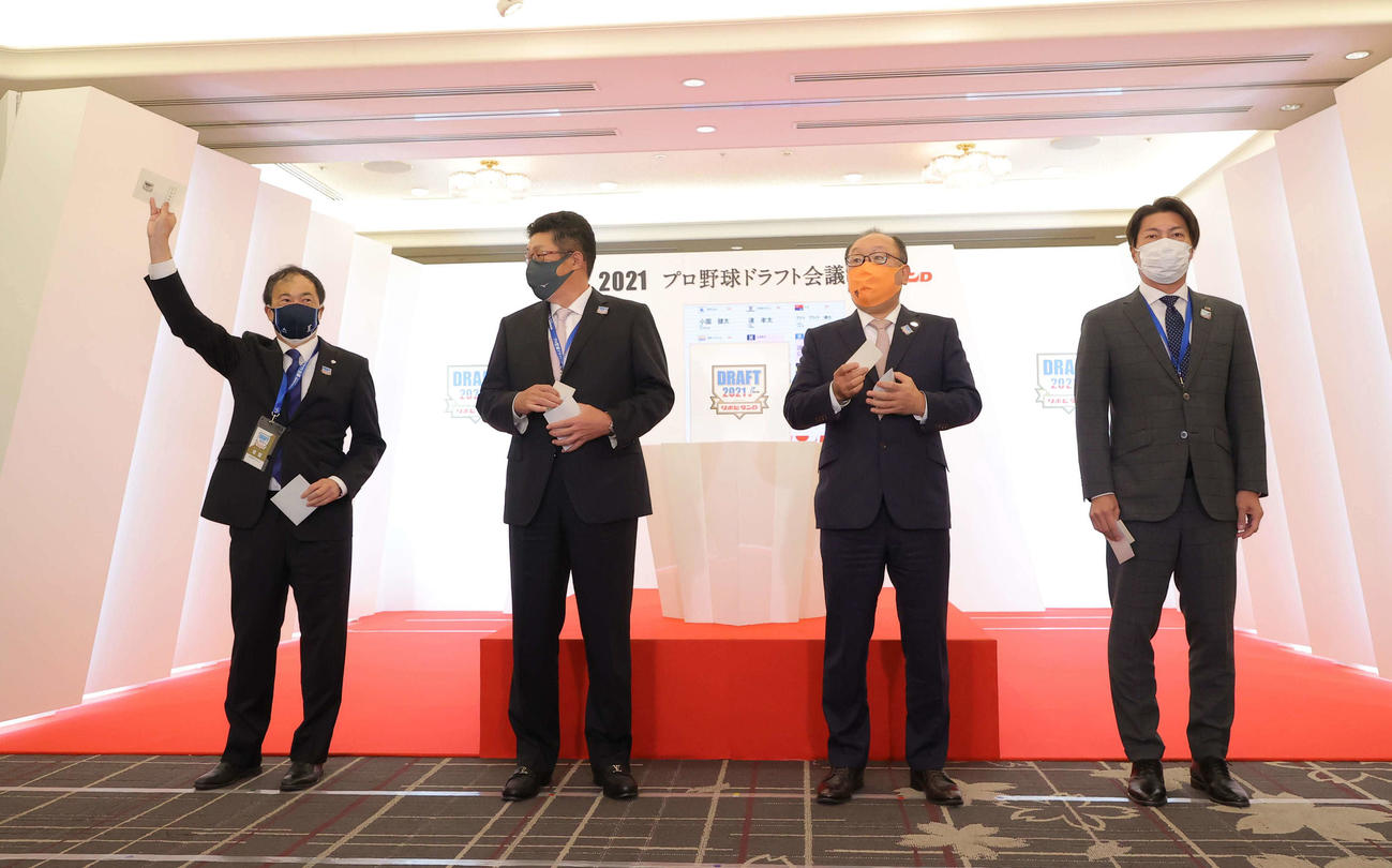 1位指名で西日本工大・隅田の交渉権を獲得した西武飯田球団本部長（左）は当たりくじを掲げる。右へ広島佐々岡監督、巨人今村社長、ヤクルト高津監督（代表撮影）