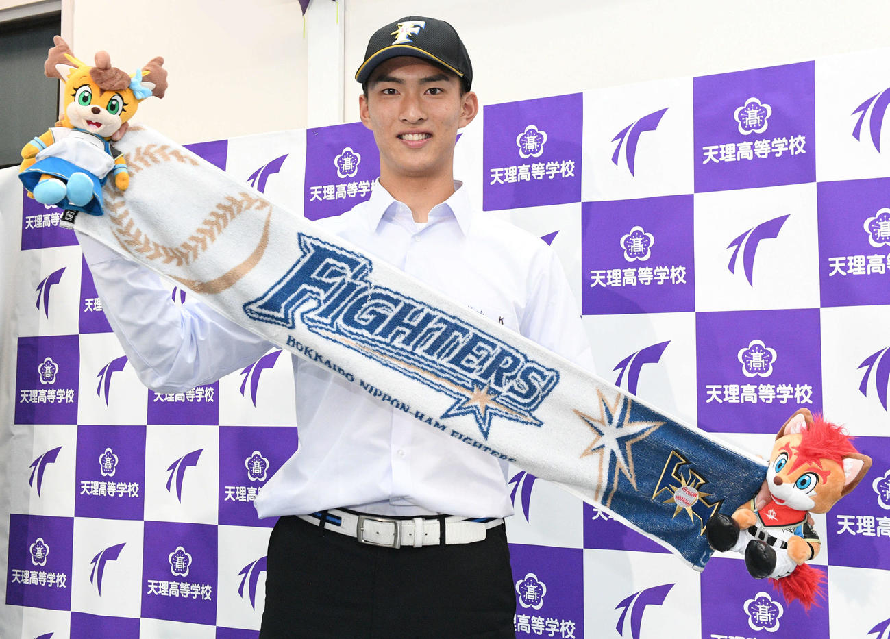 日本ハムから1位に指名された天理・達は、球団グッズを手に笑顔を見せる（撮影・滝沢美穂子）