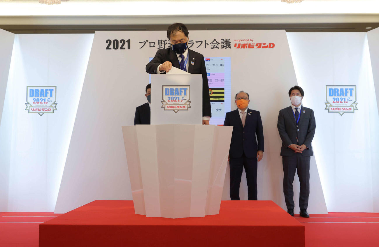 1位指名の西日本工大・隅田の抽選でくじを引く西武飯田球団本部長（手前）。後方左から広島佐々岡監督、巨人今村社長、ヤクルト高津監督（代表撮影）