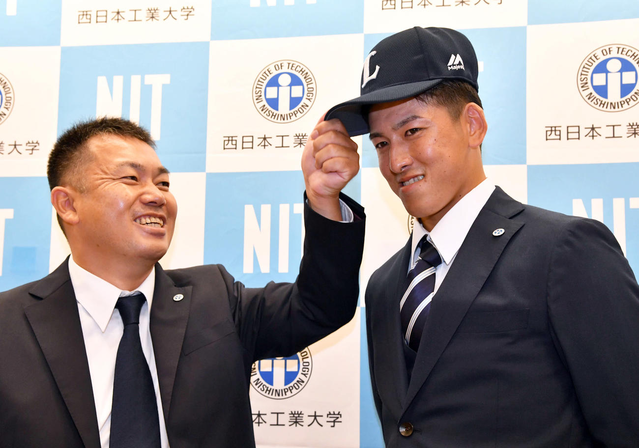 4球団競合で西武に1巡目で指名され、武田監督（左）から帽子をかぶせてもらう隅田（撮影・岩下翔太）
