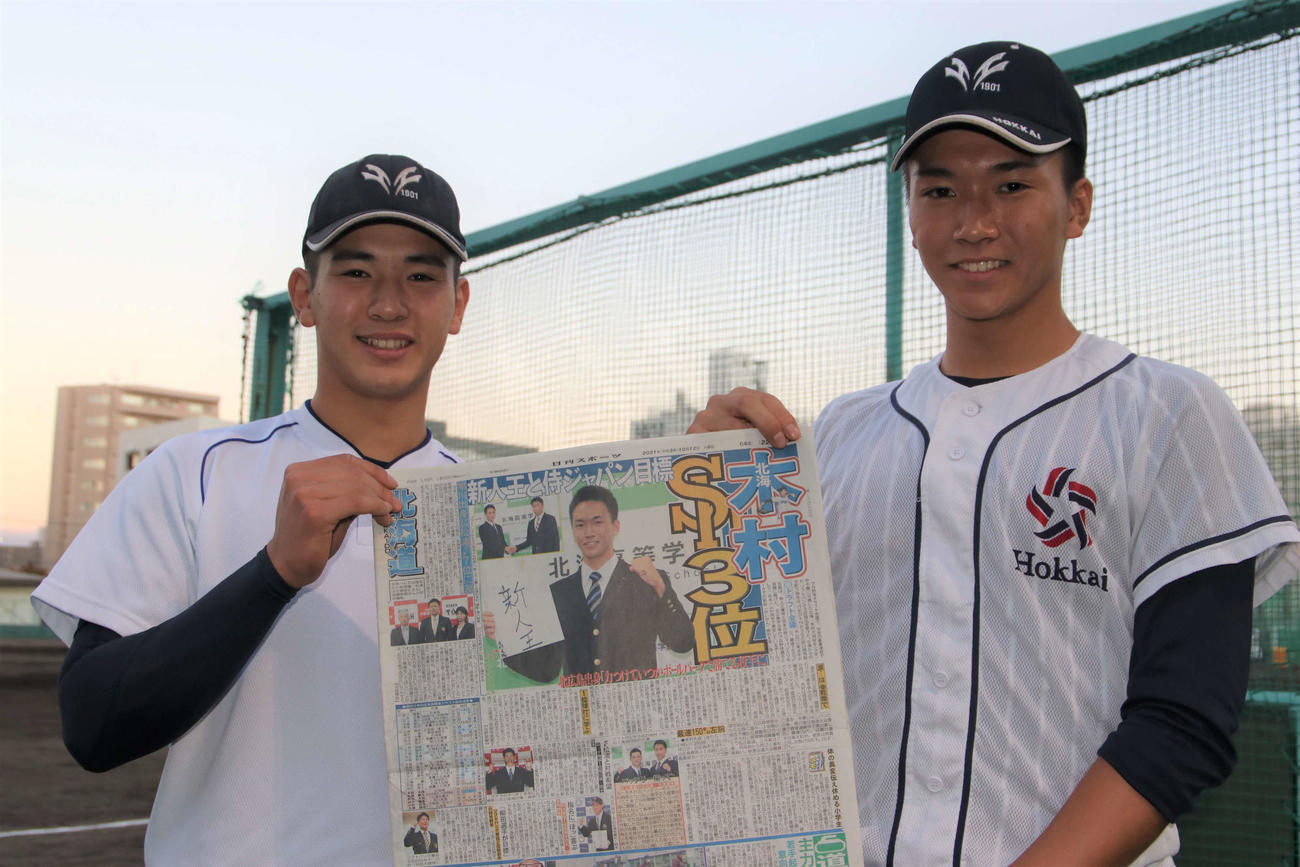 ドラフト会議から一夜明け、結果を報じる日刊スポーツ北海道版を手に笑顔を見せる北海の大津（左）と木村（撮影・山崎純一）