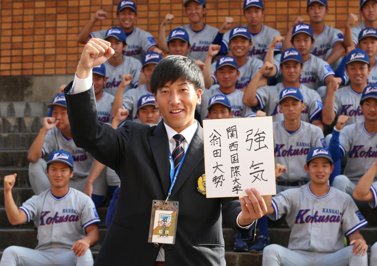巨人のドラフト1位指名あいさつを受けた関西国際大・翁田は、色紙に「強気」と記してガッツポーズ（撮影・上山淳一）