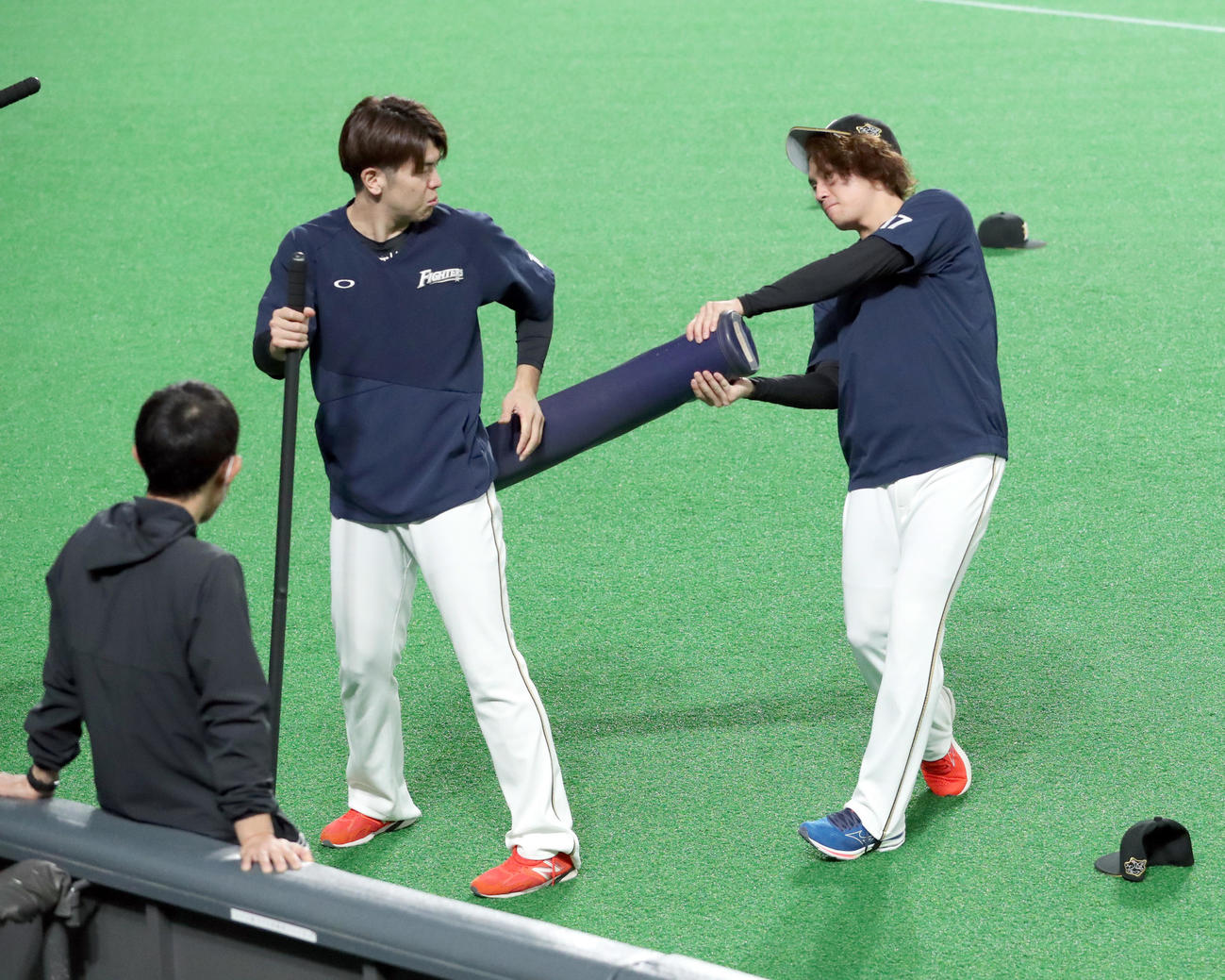 日本ハム対西武　試合前、日本ハム清水（左）は伊藤にトレーニングポールでお尻をたたかれる（撮影・佐藤翔太）
