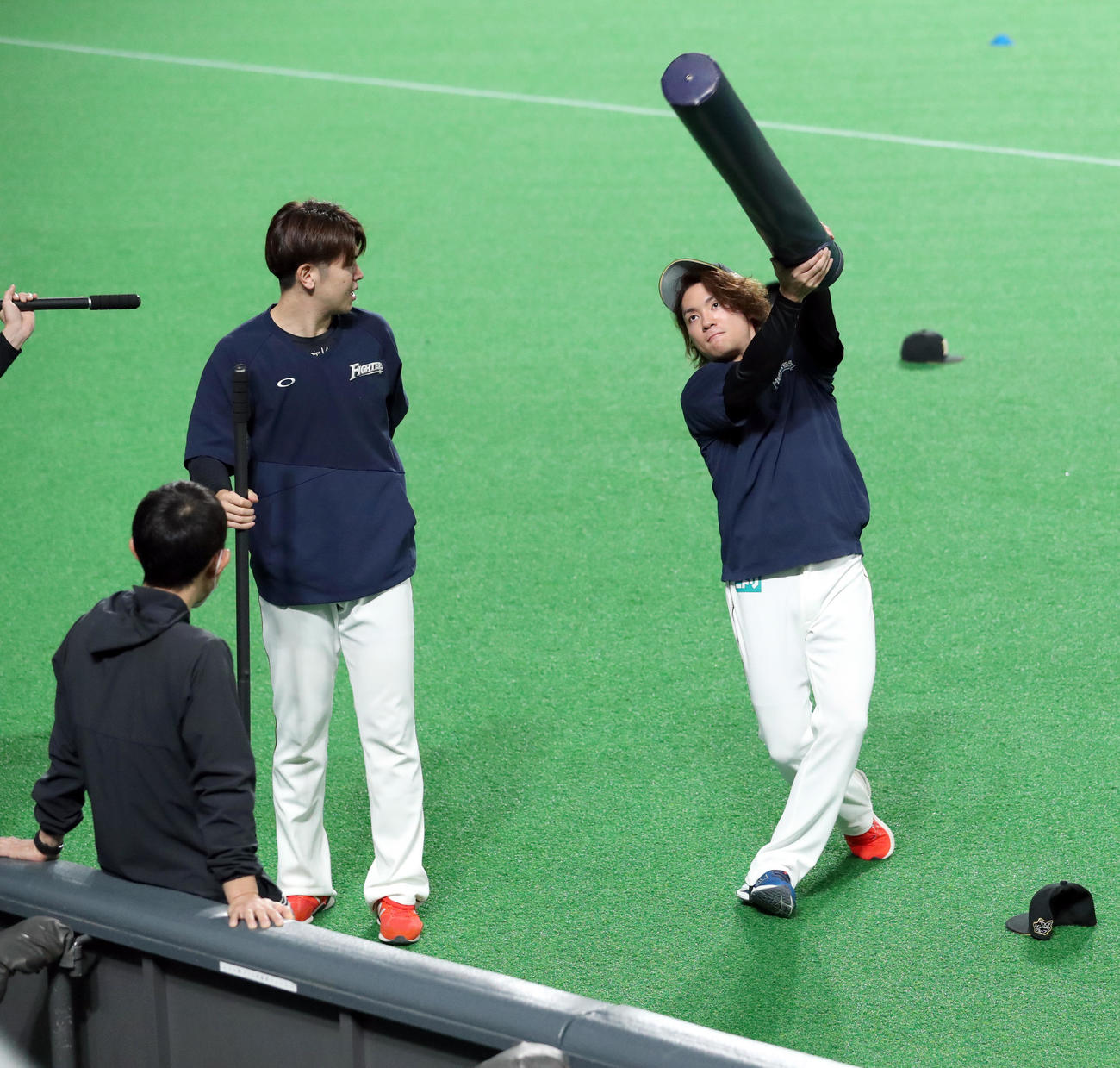 日本ハム対西武　試合前、日本ハム清水（左）は伊藤にトレーニングポールでお尻をたたかれる（撮影・佐藤翔太）