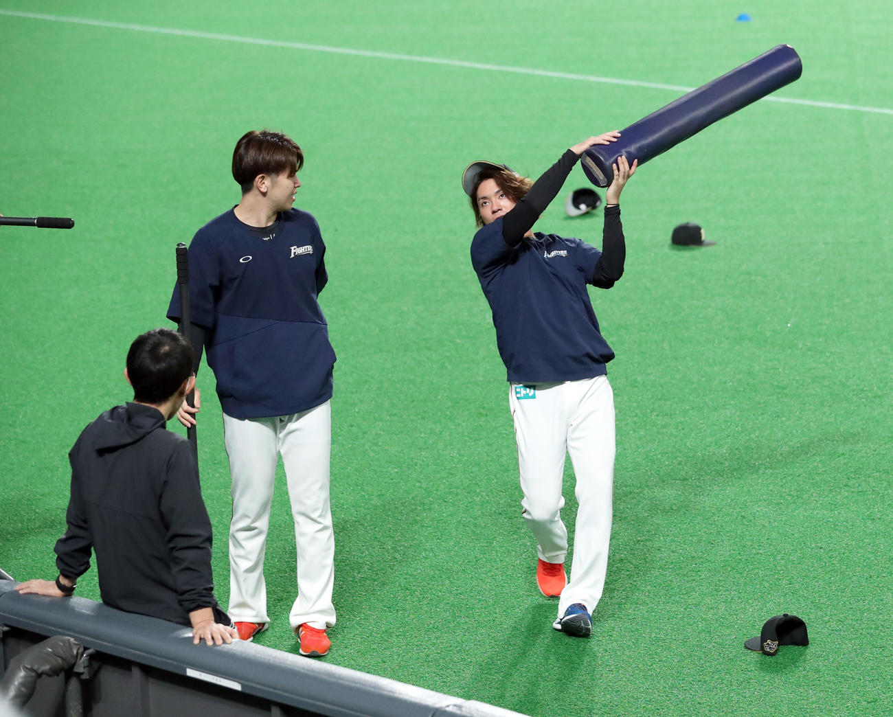 日本ハム対西武　試合前、日本ハム清水（左）は伊藤にトレーニングポールでお尻をたたかれる（撮影・佐藤翔太）