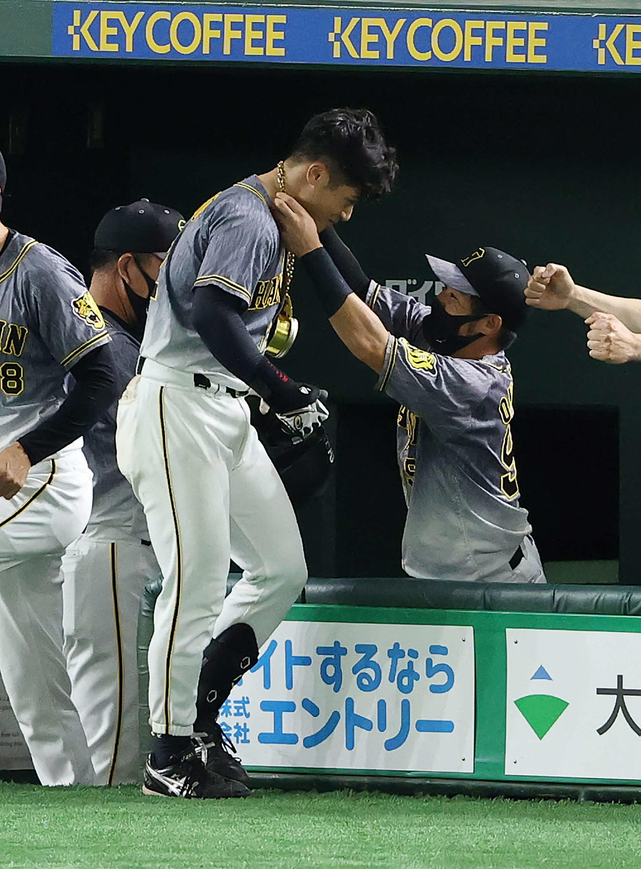 巨人対阪神　4回表阪神2死、左越え本塁打を放った坂本（左）はベンチ前でメダルをもらう（撮影・河野匠）