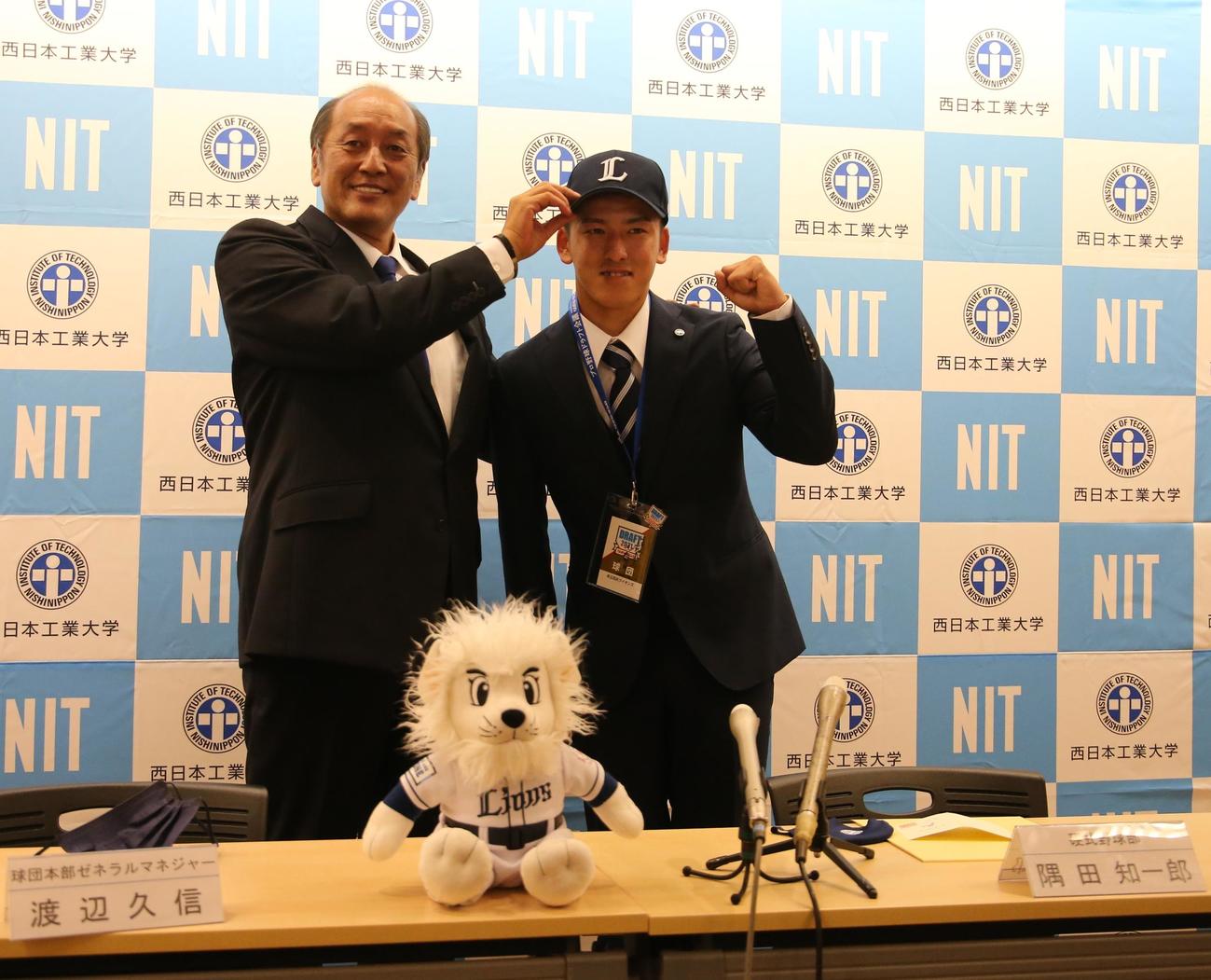 西武からドラフト1位の指名あいさつを受け、渡辺久信GMから帽子をかぶせてもらう西日本工大・隅田知一郎投手（撮影・菊川光一）