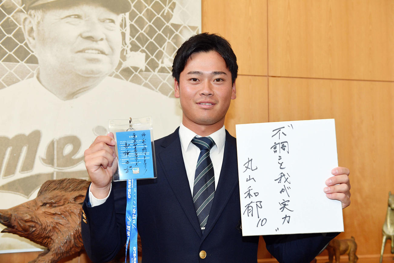 指名あいさつで受け取ったヤクルト高津監督直筆メッセージ入りのドラフト会議IDパスと座右の銘「不調こそ我が実力」と記した色紙を手にするドラフト2位の明大・丸山（撮影・滝沢徹郎）