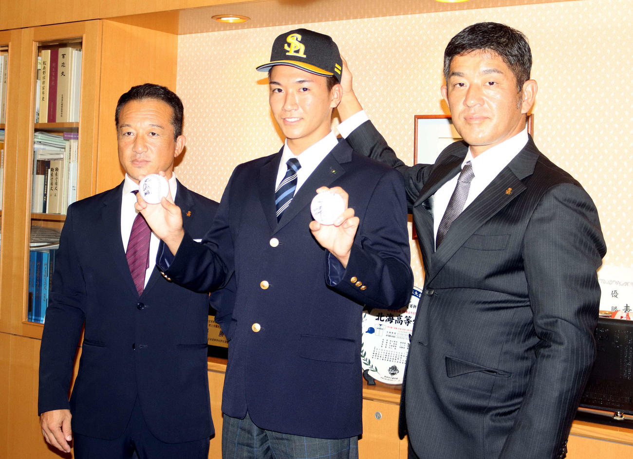 指名あいさつを受け、右手にソフトバンク王会長、左手に工藤監督のサインボールを持つ北海・木村（中央）。左はソフトバンク作山アマスカウトチーフ補佐、右は同福山アマスカウトチーフ（撮影・永野高輔）