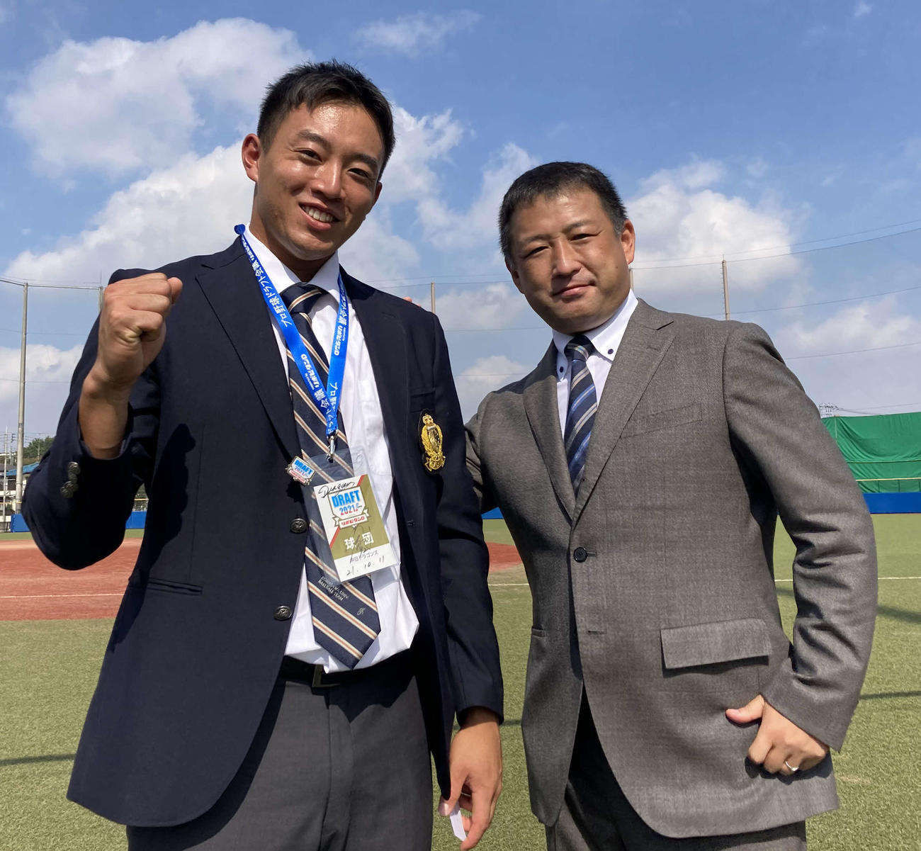 中日正津スカウト（右）からドラフト会議入館証をもらいガッツポーズする中日ドラフト2位の駒大・鵜飼航丞外野手