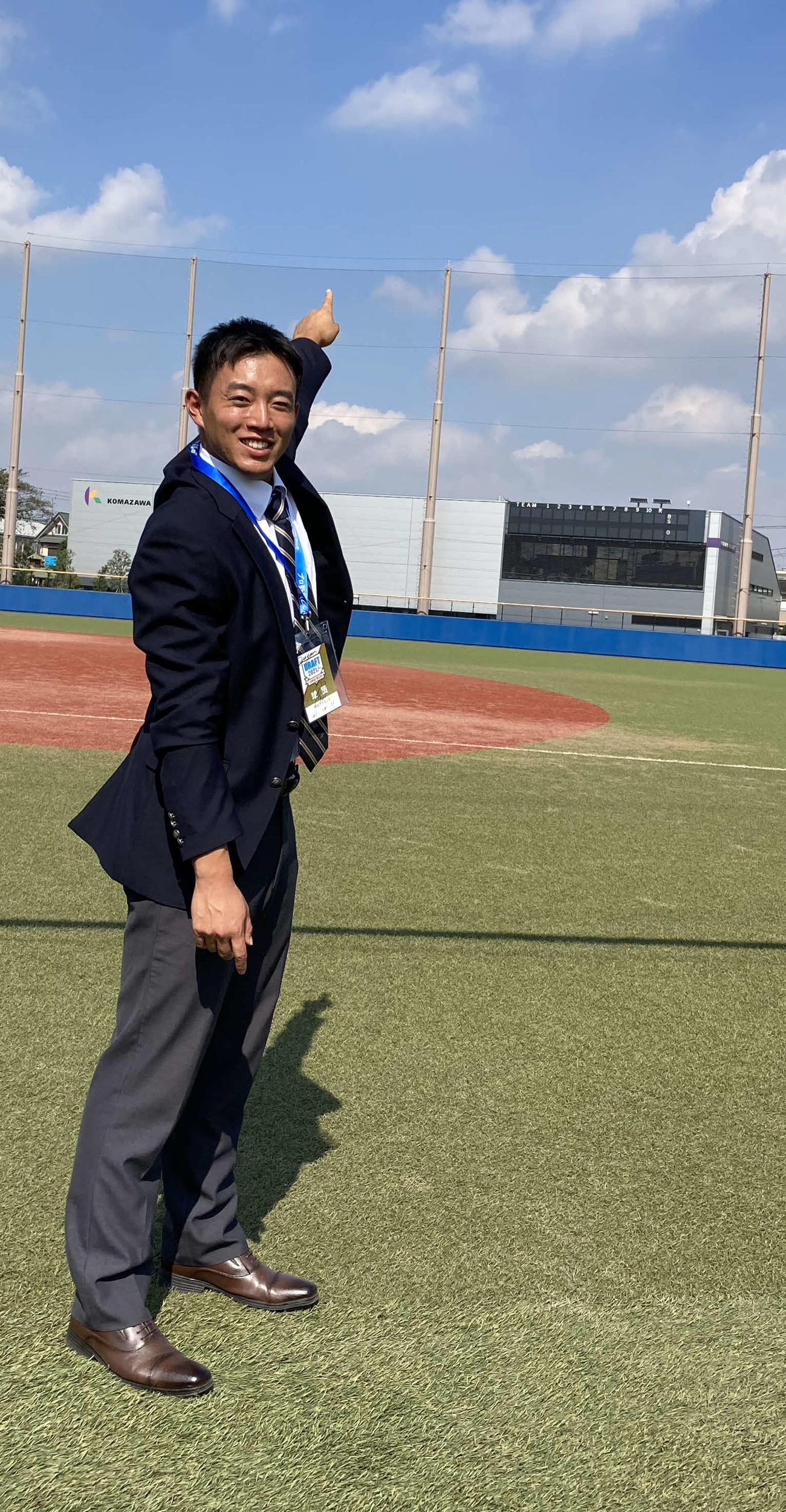 自身が越す外野の高さ30メートルのフェンスを指さす中日ドラフト2位の駒大・鵜飼航丞外野手