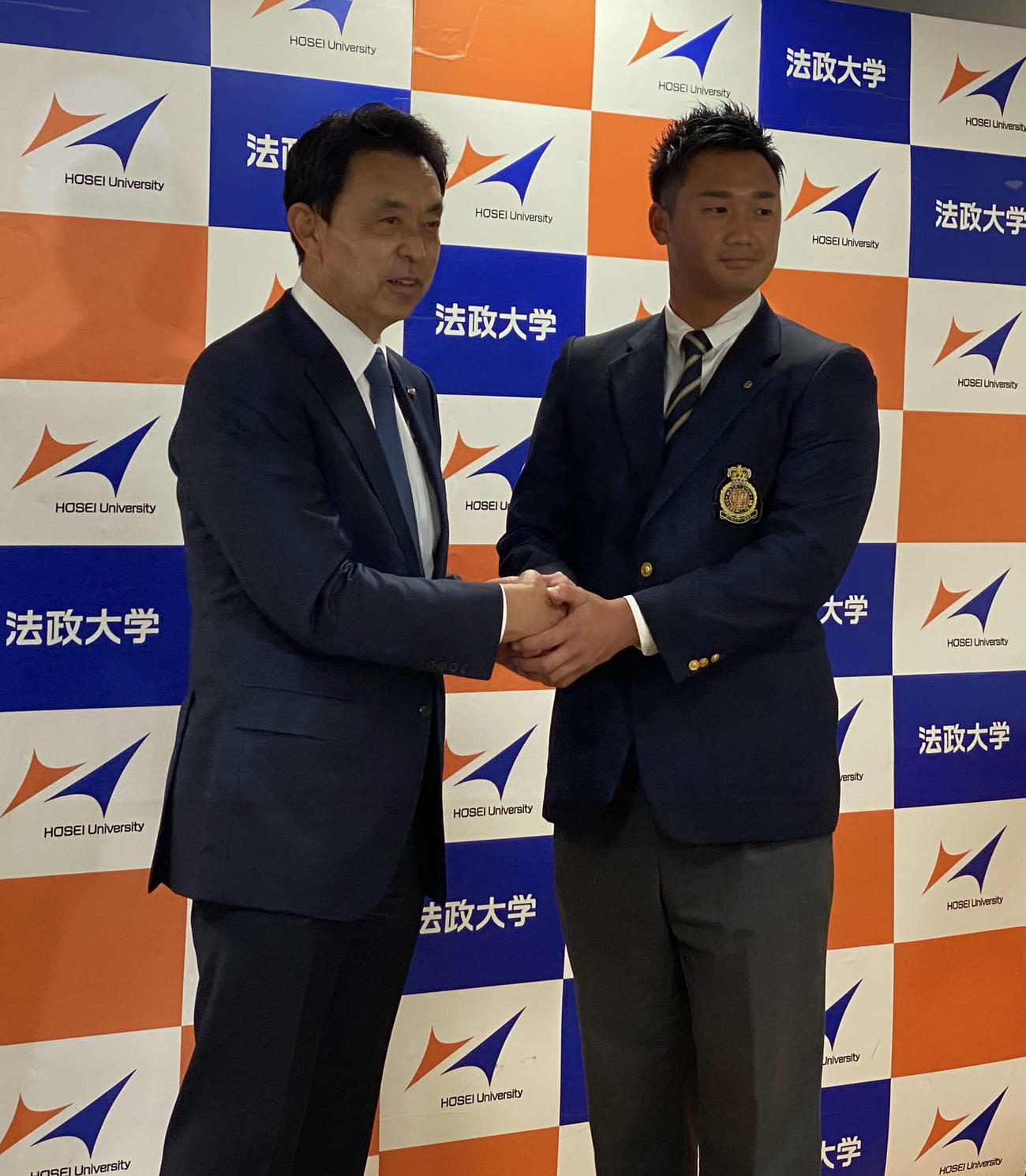 ヤクルトのドラフト1位指名あいさつを受け、小川淳司GMと握手する法大・山下輝投手（撮影・湯本勝大）