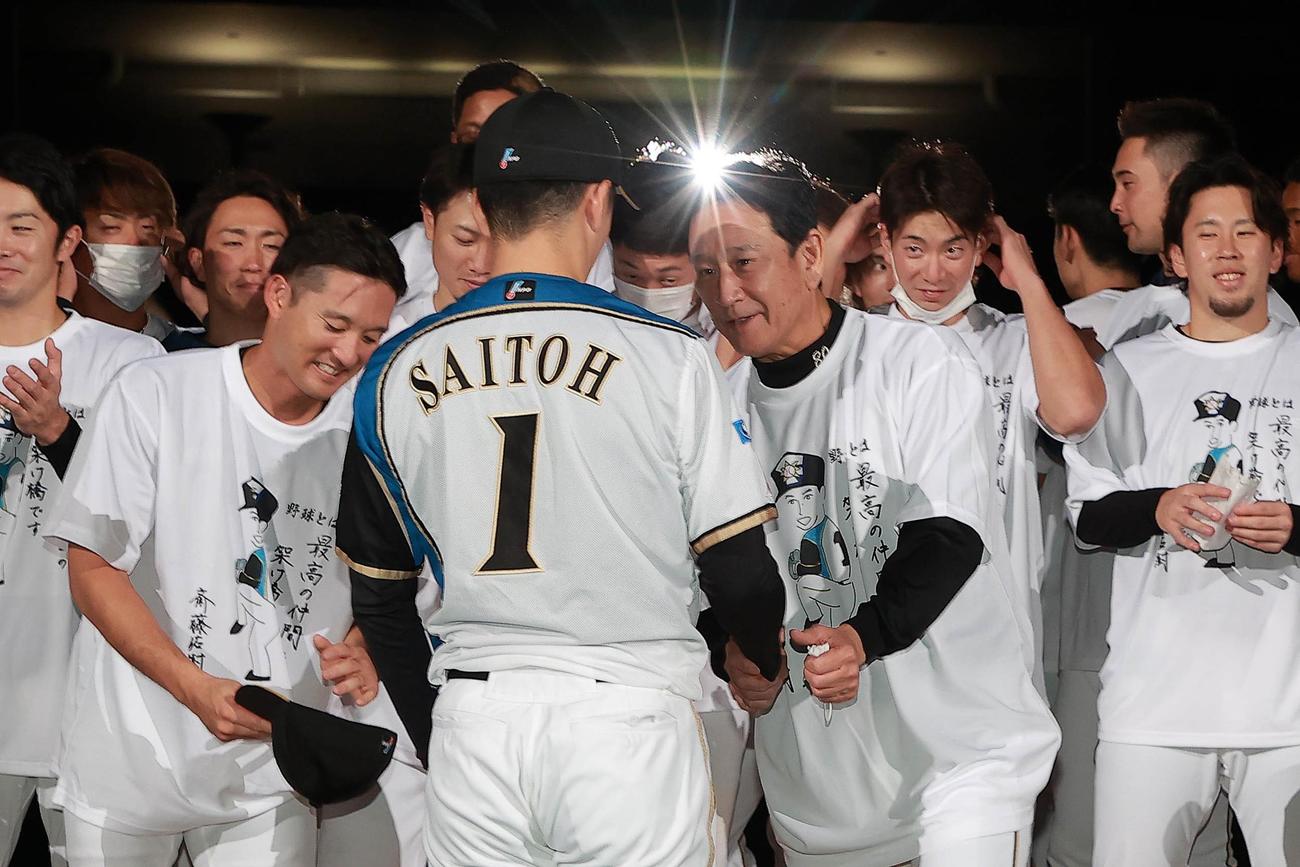 日本ハム木田2軍総合兼投手コーチがデザインしたTシャツを着て斎藤をねぎらう栗山監督ら（球団提供）