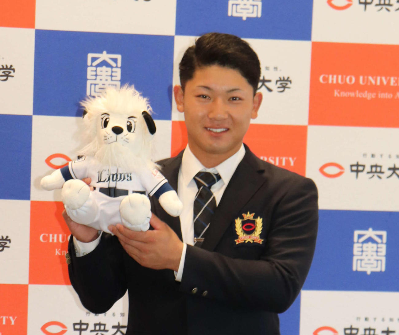 西武3位指名の中大・古賀は指名あいさつを終え、球団マスコットのレオのぬいぐるみを持ち笑顔を見せる（撮影・保坂淑子）