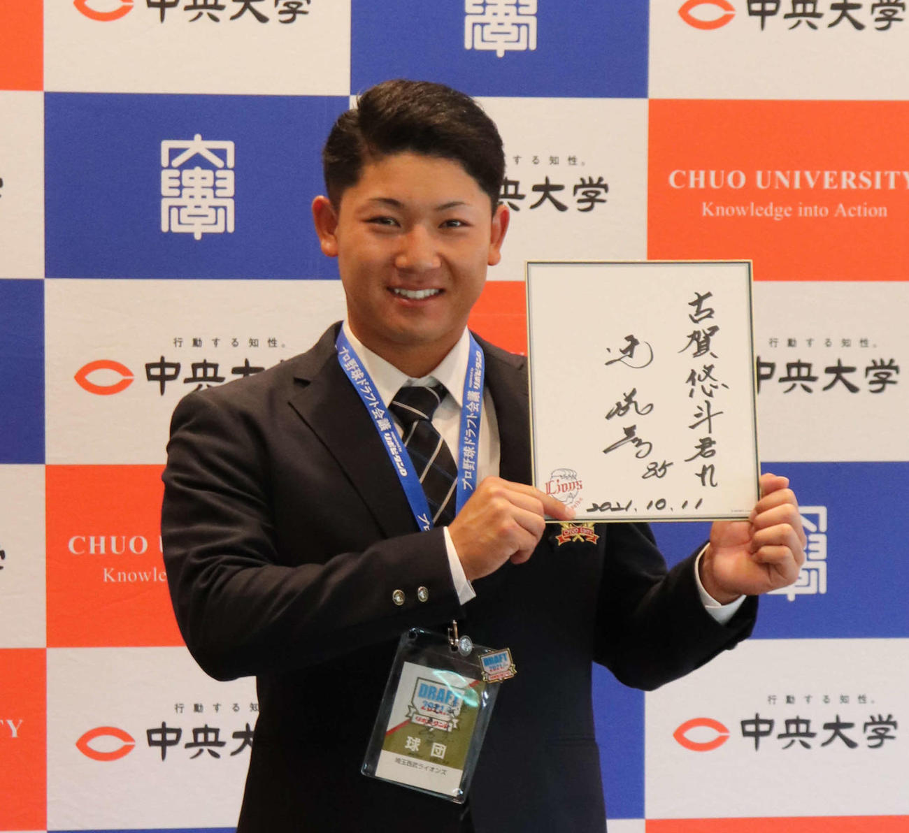 西武3位指名の中大・古賀は指名あいさつを終え、辻監督からのメッセージが書かれた色紙を持ち笑顔で記念撮影（撮影・保坂淑子）