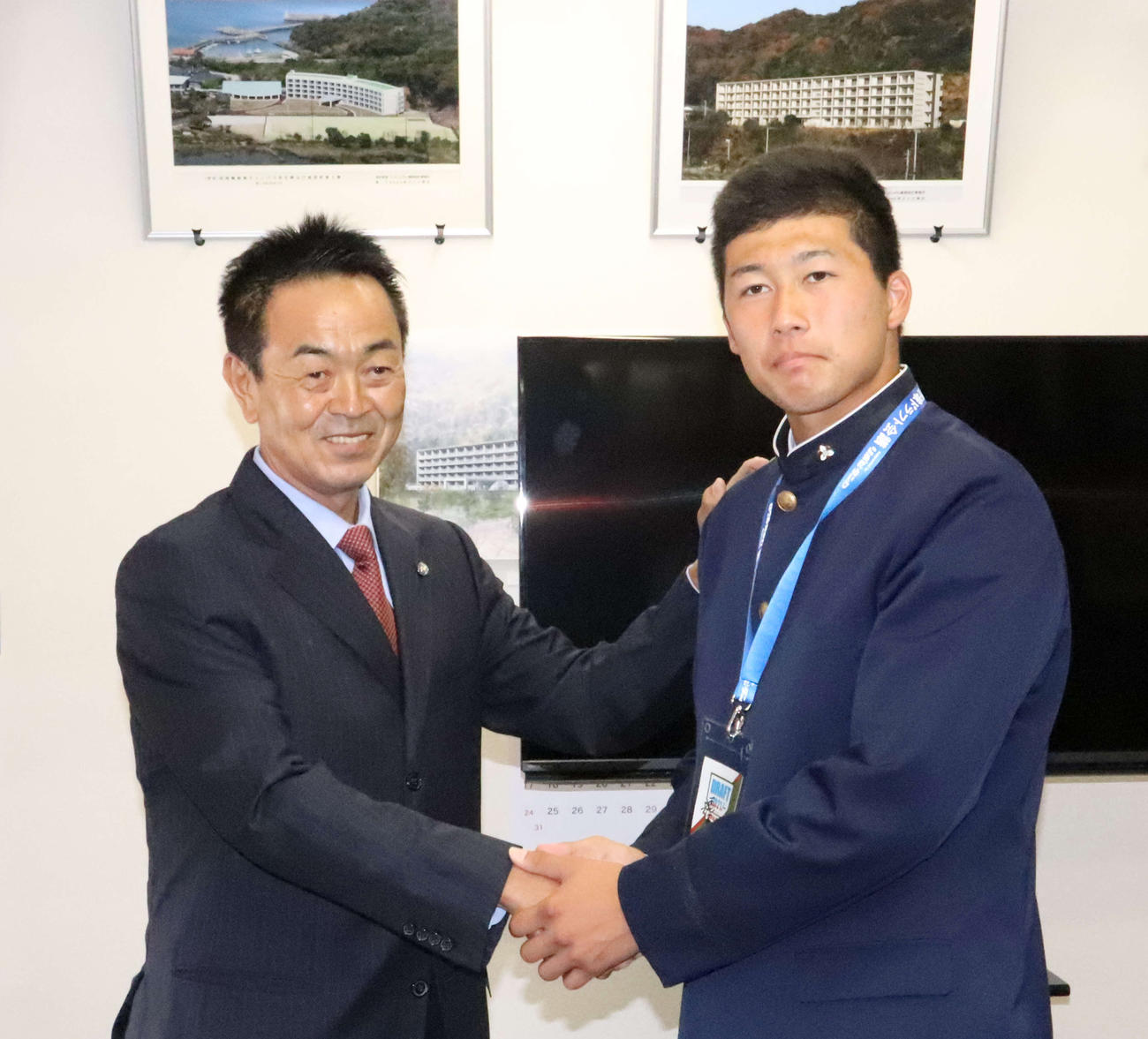 指名あいさつを受けた巨人ドラフト6位の明徳義塾・代木（右）は水野スカウト部長と握手（撮影・小早川宗一郎）