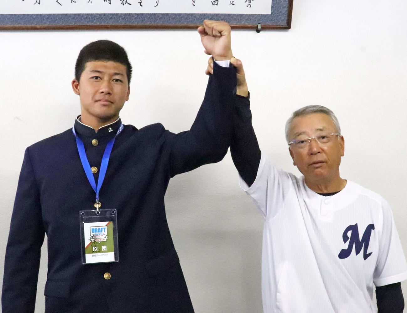 指名あいさつを受けた巨人ドラフト6位の明徳義塾・代木（左）の腕を上げる馬淵監督（撮影・小早川宗一郎）