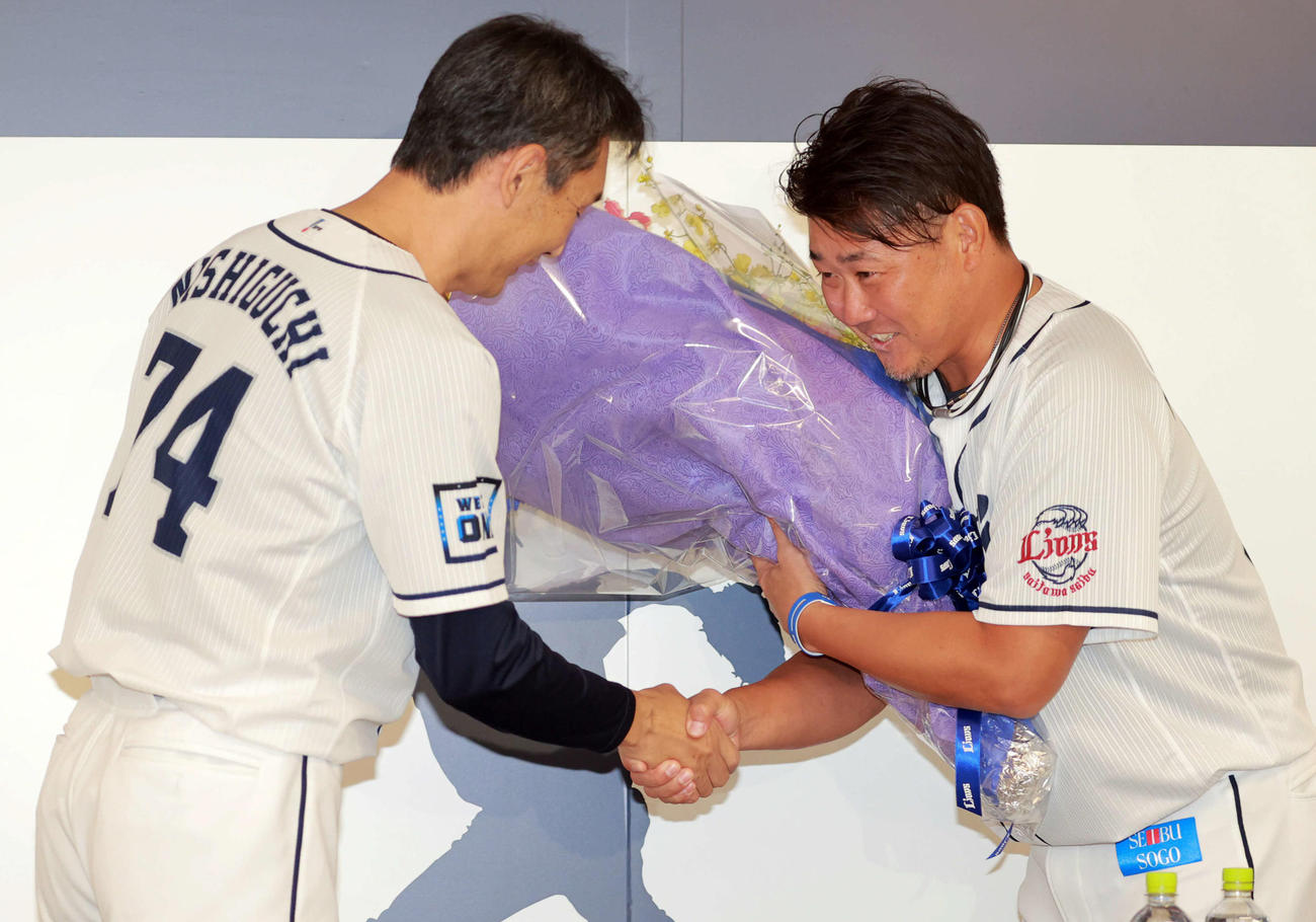 引退会見で西武西口投手コーチ（左）から花束を受け取る松坂
