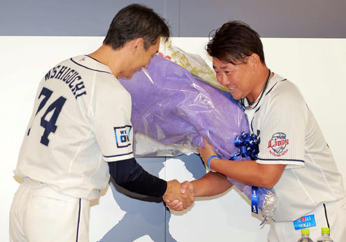 引退会見で西武西口投手コーチ(左)から花束を受け取る松坂