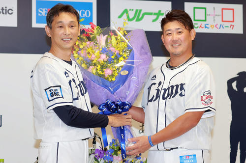 引退会見で西武西口投手コーチ(左)から花束を受け取る松坂