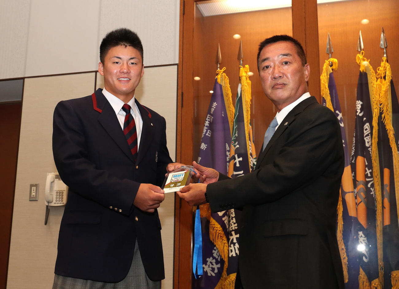 阪神の山本スカウト（右）から矢野監督のサイン入りドラフト会議の会場入場証を渡される智弁学園・前川（撮影・白石智彦）