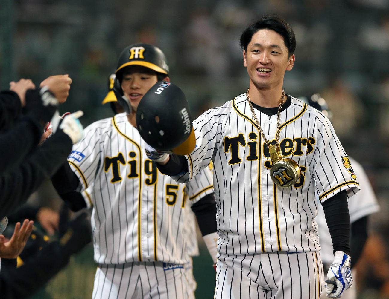 阪神対ヤクルト　1回裏阪神無死一、二塁、近本（手前）は先制の右越え3点本塁打を放ち球団ロゴ入り「虎メダル」の祝福を受ける（撮影・上山淳一）