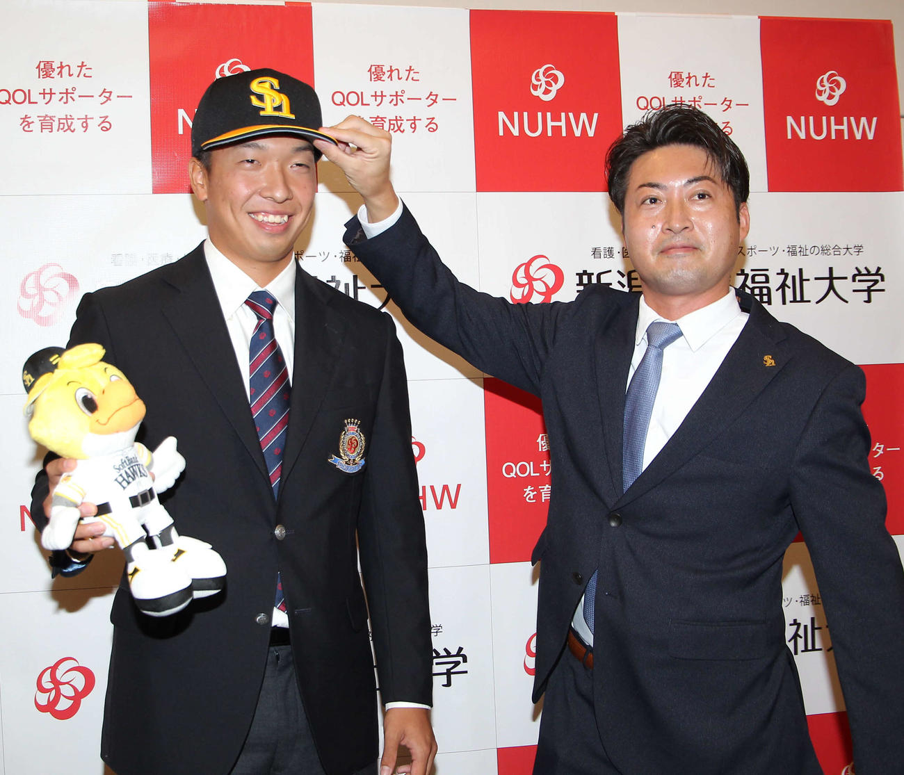 福元スカウト（右）からソフトバンクの帽子をかぶせてもにいニッコリの佐藤投手