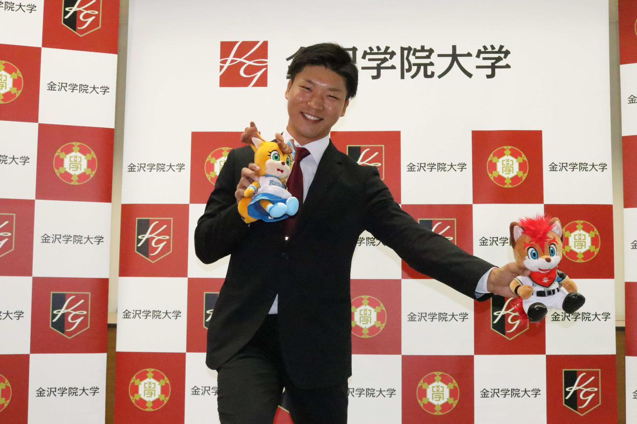 球団マスコットを手に笑顔で投球ポーズを見せる金沢学院大・長谷川（撮影・小林憲治）