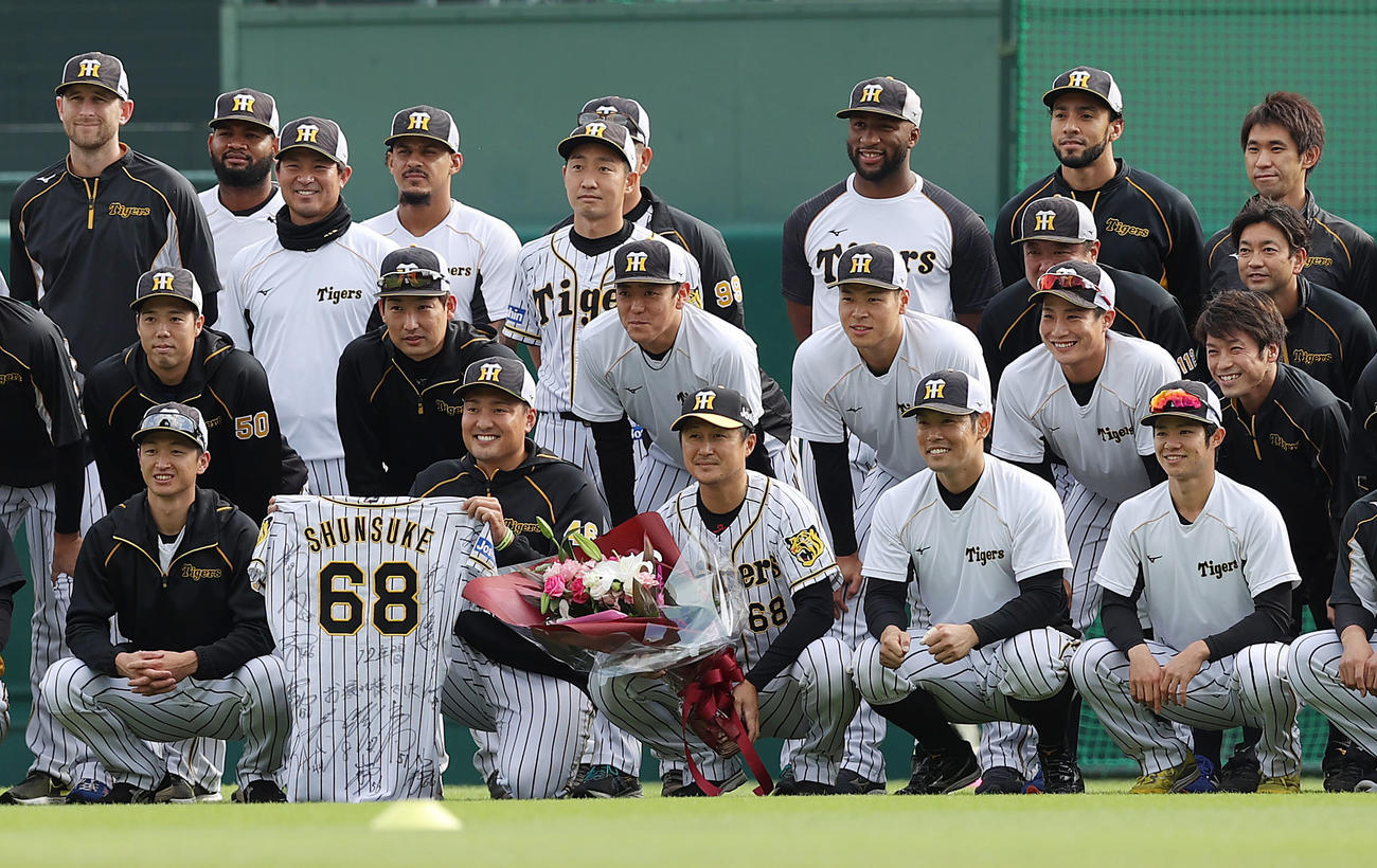 阪神対中日　練習前、ナインから花束と寄せ書きユニホームが贈られ、記念撮影する今季限りで引退する阪神俊介（前列中央）（撮影・前田充）