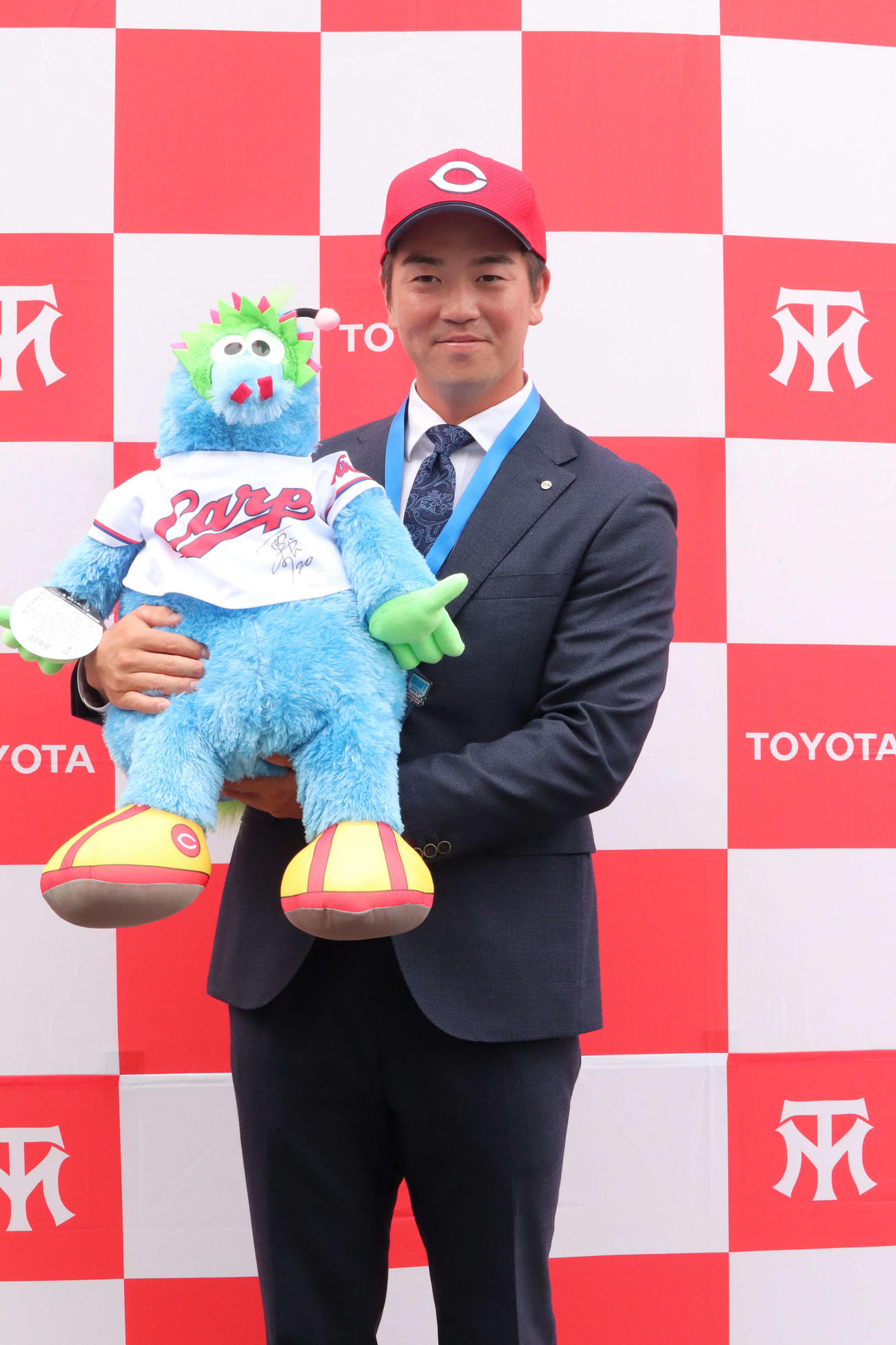 栗林からトヨタ自動車に贈られたスラィリー人形を抱っこする広島ドラフト3位トヨタ自動車・中村健人外野手（撮影・前原淳）