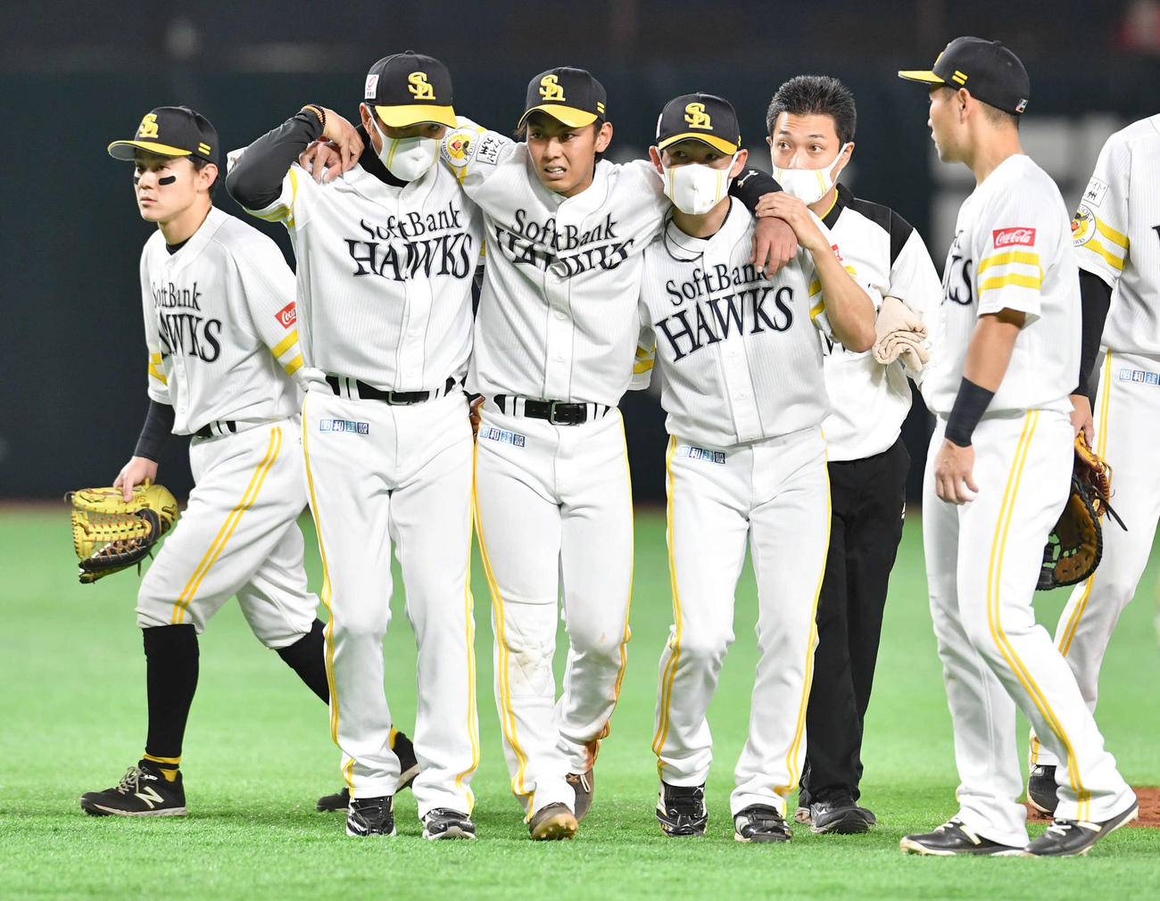 ソフトバンク対日本ハム　2回表日本ハム1死一塁、盗塁を狙った高浜と交錯して足を負傷し、小久保ヘッドコーチ（左から2人目）、本多コーチ（右から3人目）の肩を借りて立ち上がる今宮（撮影・岩下翔太）
